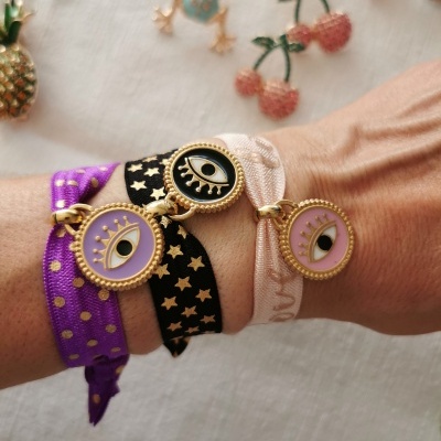 Pulseiras em tecido com pendentes dourados e olhos estilizados no pulso