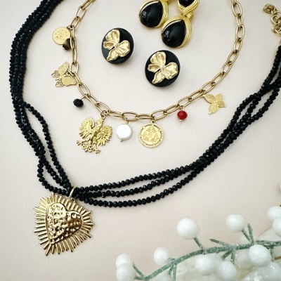 Conjunto de colar, pulseira e brincos dourados com pedras pretas e detalhes de borboletas e coração