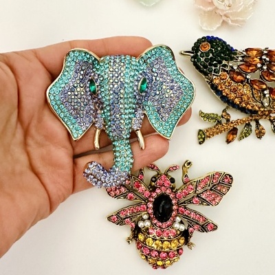 Broches decorativos de elefante, abelha e pássaro com pedras brilhantes em fundo branco