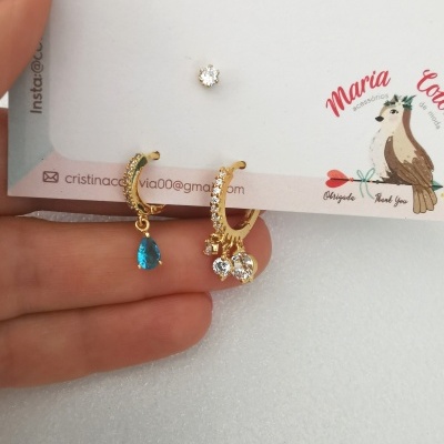 Conjunto de brincos dourados com pedras azuis e transparentes em cartão de marca