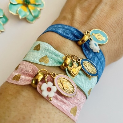 Pulseiras coloridas de tecido com pendentes dourados no braço