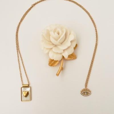 Colares dourados com pingentes e broche de flor branca e folhas douradas
