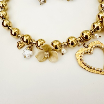 Colar dourado com pendentes variados sobre fundo branco