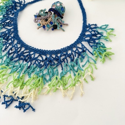 Colar de contas coloridas com broche decorativo de pedras