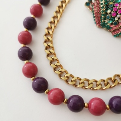Colar de contas rosa e roxas com corrente dourada e broche colorido