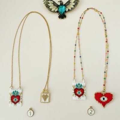 Broche de pássaro azul e bege e três colares com pingentes de contas coloridas, dois pendurados em correntes douradas, em fundo claro.