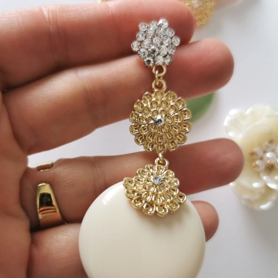 Brinco com pendente branco e detalhes dourados com pedras brilhantes