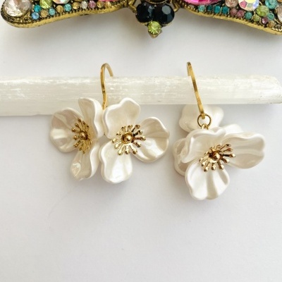 Brincos florais brancos com centro dourado e acessório colorido de pedras