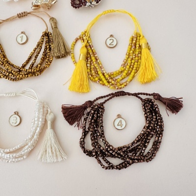 Quatro pulseiras coloridas de contas com franjas e etiquetas numeradas