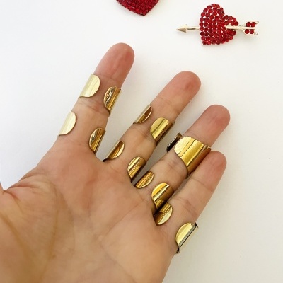 Mão com anéis metálicos dourados e dois corações vermelhos decorativos sobre fundo branco