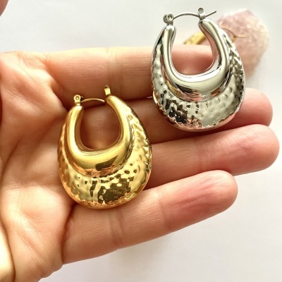 Brincos de argola dourado e prateado com textura martelada numa mão