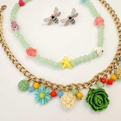 Conjunto de bijuterias com brincos de abelha, colar de contas verdes com pendentes marinhos e colar dourado com flores coloridas