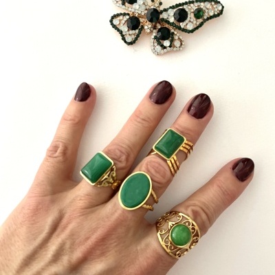 Mão com anéis de pedras verdes e broche borboleta decorativo