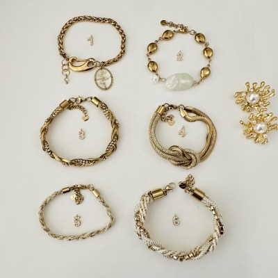 Seis pulseiras douradas e prateadas e um par de brincos dourados com pérola.