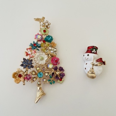 Broches de Natal, uma árvore decorada e um boneco de neve com gorro e cachecol vermelhos