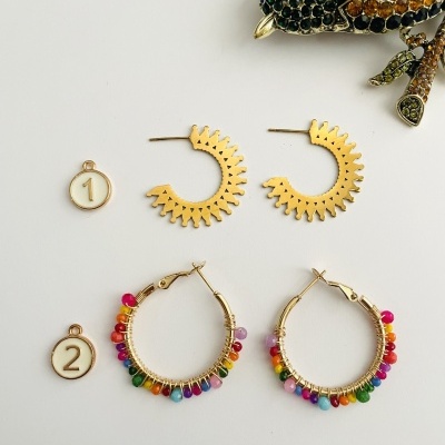 Dois pares de brincos dourados com etiquetas numeradas em fundo branco.