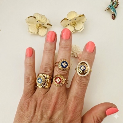 Mão com anéis dourados decorados e unhas corais