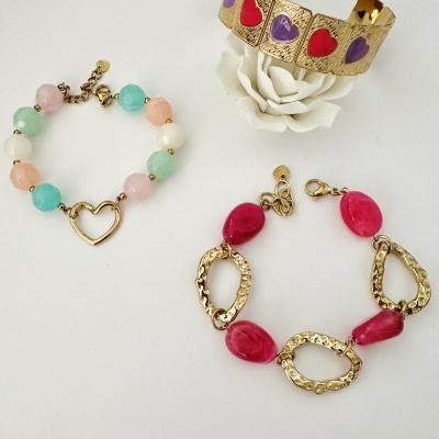 Três pulseiras coloridas e douradas sobre fundo branco