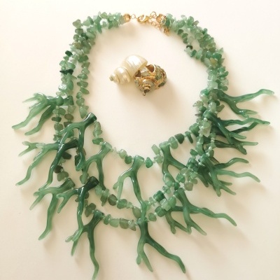 Colar verde com pendentes que parecem corais e conchas sobre fundo branco