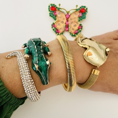 Três pulseiras distintas em pulso com fundo branco e borboleta decorativa colorida