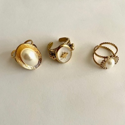 Três anéis dourados com pérolas e detalhes em padrão