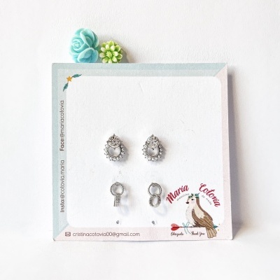 Brincos de prata em cartão decorativo com flores artificiais