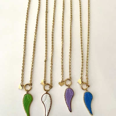 Quatro colares dourados com pendentes de asas coloridas (verde, branco, lilás, azul) e pequeno coração dourado em fundo branco.