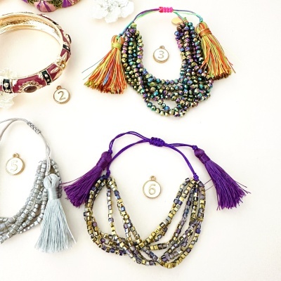 Pulseiras coloridas com miçangas e franjas numeradas sobre fundo branco