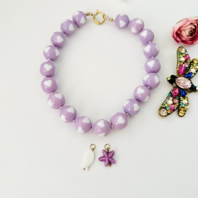 Pulseira roxa com corações brancos, relógio branco e brinco com peixe e estrela do mar.