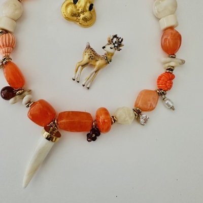 Colar de pedras laranja e creme com pingente de presa e dois broches animais