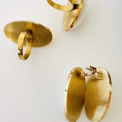 Conjunto de anéis e brincos dourados com base oval sobre fundo branco