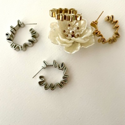 Brincos em forma de argola ondulada cinzentos e dourados com flor branca decorativa