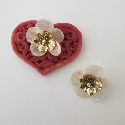 Broche flor branco dourado sobre coração vermelho decorativo