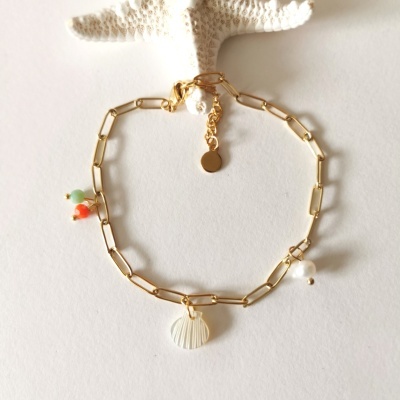 Pulseira dourada com pingente concha e pequenos pendentes coloridos sobre fundo claro com estrela do mar