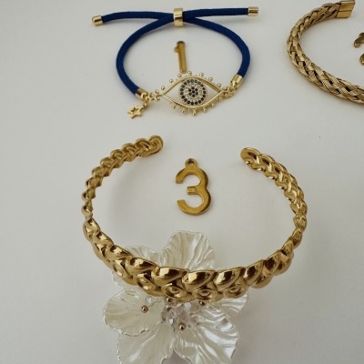 Pulseiras e pendentes dourados e azul sobre fundo branco.