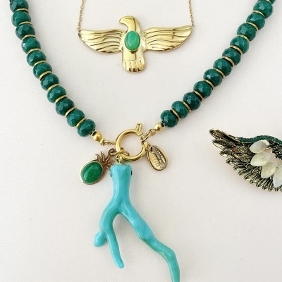 Colares com bolas verdes e pendentes dourados e azul turquesa sobre fundo branco