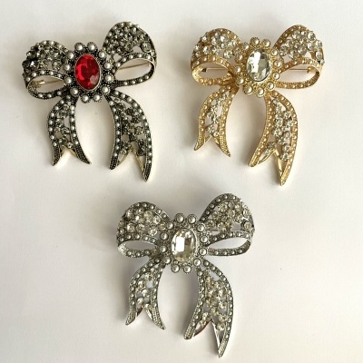 Broches em forma de laço em metal prateado e dourado com cristais decorativos