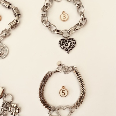 Duas pulseiras prateadas com corações e estrela em fundo branco