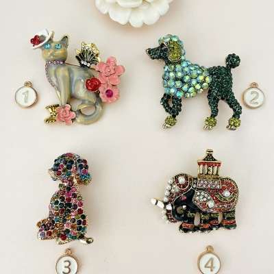 Broches decorativos de gato, poodle, cão e elefante com pedras brilhantes sobre fundo claro