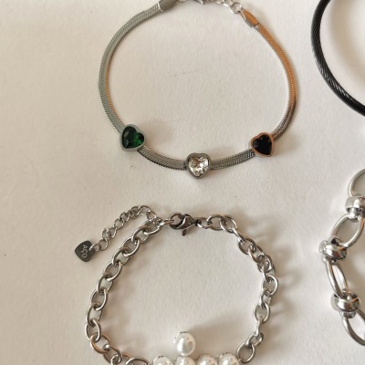 Pulseiras de elos e fina com corações e pérolas sobre fundo branco