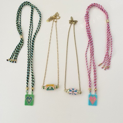 Quatro colares com pendentes bordados em miçangas coloridas em fundo branco