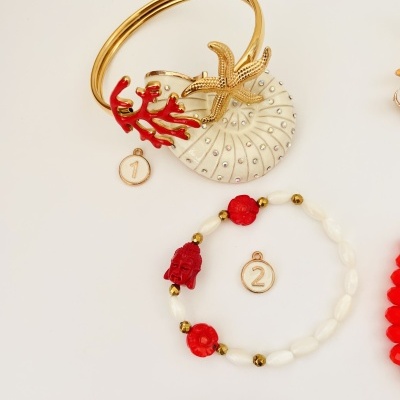 Pulseira dourada com estrela-do-mar e coral vermelho e pulseira de contas brancas e vermelhas com rosto vermelho