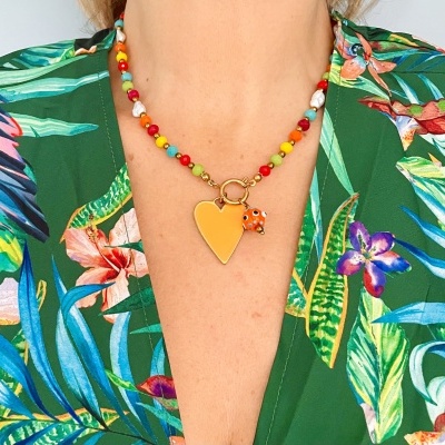 Colar colorido com pendente amarelo e animal laranja, camisa verde com padrão floral