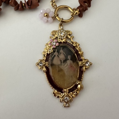 Pendente dourado vintage com flores, pedras brilhantes e imagem retro num fundo branco