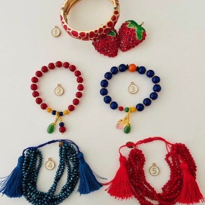 Cinco peças de bijuteria coloridas sobre fundo branco, incluindo pulseiras e colares numerados de 1 a 5.