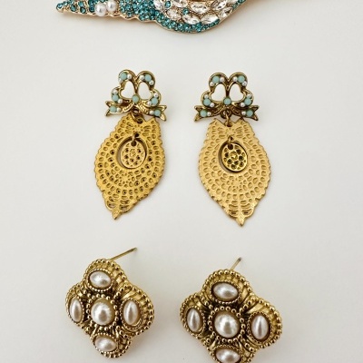 Conjunto de joias douradas com pedras azuis e pérolas sobre fundo branco