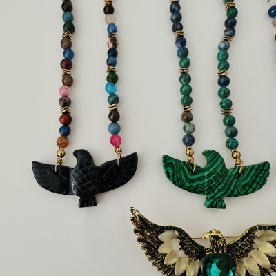 Colares com contas coloridas e pendentes em forma de aves, preto, verde e dourado.