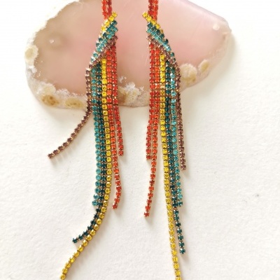 Brincos pendentes coloridos sobre pedra rosa