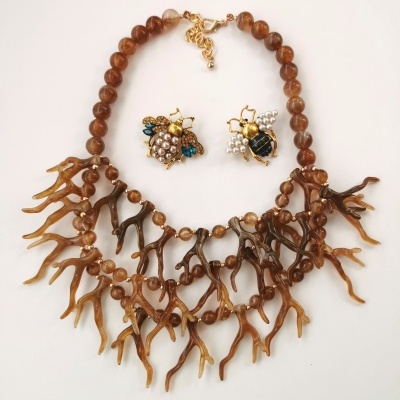 Colar de contas castanhas e brincos de abelha em fundo branco