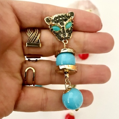 Brinco pendente com cabeça de leopardo dourada e esferas azuis em mão com anéis